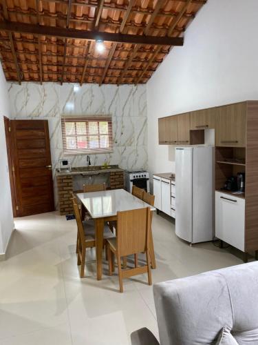 a kitchen with a table and a refrigerator at Casa Lilás no Vale do Capão in Vale do Capao