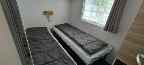une petite pièce avec un lit et une fenêtre dans l'établissement Mobil home accueillant à Aureilhan avec piscine partagée, 34 m², à Aureilhan