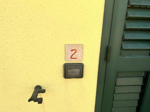 a yellow wall with a door with a number on it at Residence Sulcis 2 in Masainas