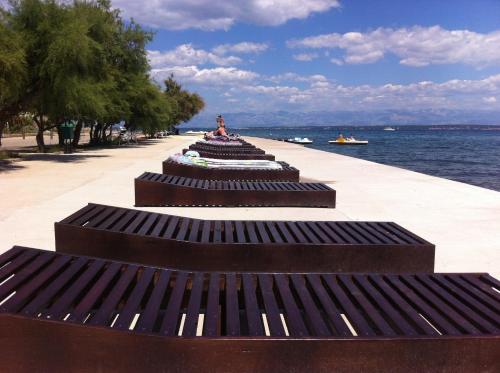 a row of benches on a sidewalk next to the water at Apartments Elena in Ugljan