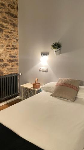 a white bed in a bedroom with a stone wall at As Miguiñas do Cebreiro in Pedrafita do Cebreiro