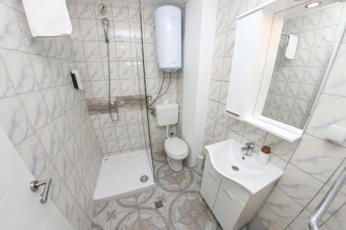 a white bathroom with a toilet and a sink at Guest House LIKE in Sarajevo