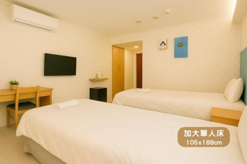 a hotel room with two beds and a desk at Elizabeth Hotel in Taichung