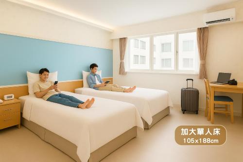 two people sitting on beds in a hotel room at Elizabeth Hotel in Taichung