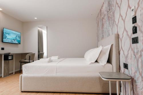 a white bedroom with a bed and a table at Ermes Luxury Hotel in Durrës
