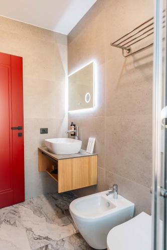 a bathroom with a white sink and a red door at Ermes Luxury Hotel in Durrës