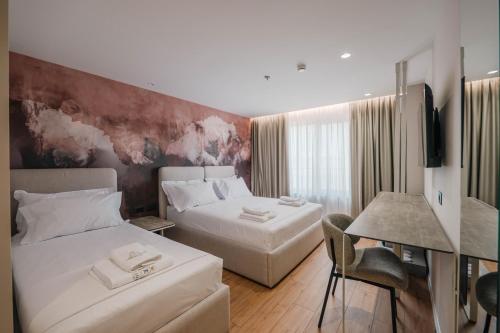 a hotel room with two beds and a desk at Ermes Luxury Hotel in Durrës
