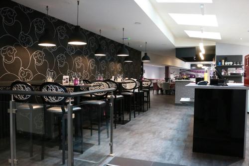 un restaurant avec des murs noirs et or et des tabourets noirs dans l'établissement Hôtel - Restaurant Eugenie, à Pontorson