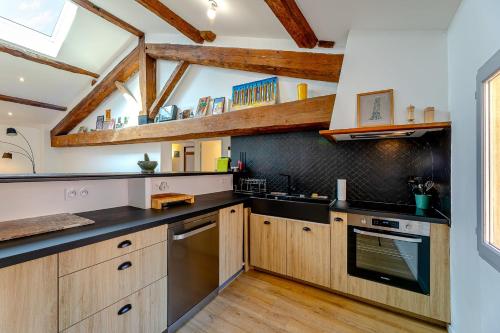 une cuisine avec des placards en bois et des comptoirs noirs dans l'établissement L'Augustin- Coeur de ville - Wifi, à Perpignan