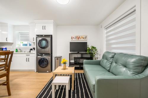 a living room with a green couch and a kitchen at A cozy and stylish 2-bedroom retreat in Surrey