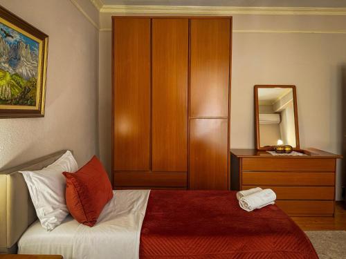 a bedroom with a bed and a dresser and a mirror at All Seasons Apartments - Free Parking & City Center in Shkodër
