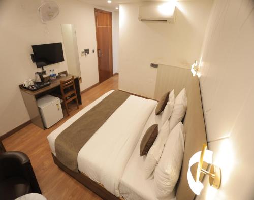 a bedroom with a bed and a desk with a television at Hotel Royal Galaxy Blest Park in New Delhi