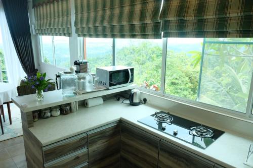 a kitchen with a counter with a microwave and a window at Sinurambi Cottage Rental in Penampang