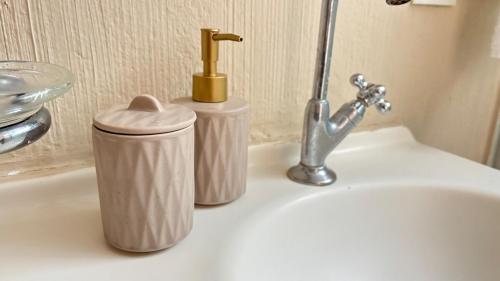 a bathroom sink with two soap dispensers and a faucet at 600m da UFV e 100m da rodoviária in Viçosa