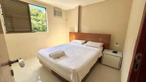 a bedroom with a bed with white sheets and a window at 600m da UFV e 100m da rodoviária in Viçosa