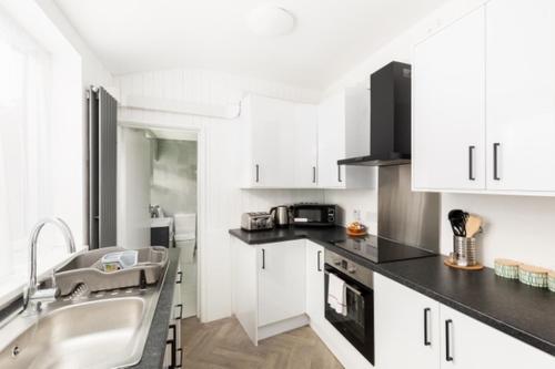 a kitchen with white cabinets and a sink at Oldbury House - Bespoke for Contractors in Smethwick