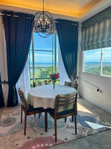 a dining room with a table and chairs and windows at Sinurambi Cottage Rental in Penampang