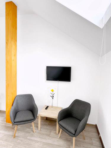two chairs and a table in a room with a tv at Penzion U Hradeb in Znojmo