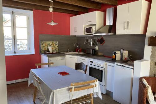 a kitchen with a table and a kitchen with white cabinets at Gîte les hortensias in Saint-Moreil