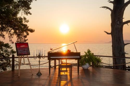 a piano sitting on a deck with the sunset in the background at Lov Faralya Adults Only in Faralya