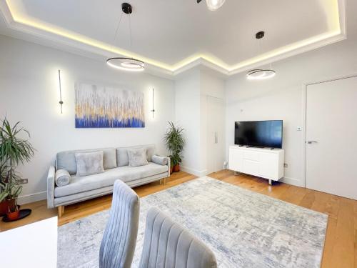 a living room with a couch and a tv at Stylish One Bed Flat in Paddington Pool and gym next door Free secure underground parking nearby in London