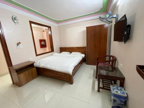 Un dormitorio con una cama, una mesa y un espejo. en Homey Hotel, en Lào Cai