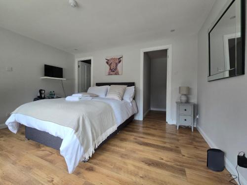 a white bedroom with a large bed and wooden floors at Tullochard Guest House in Alness