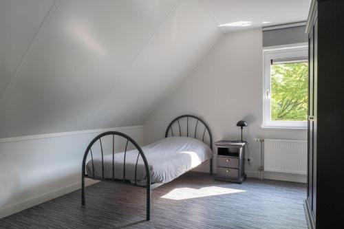 a white bedroom with a bed and a window at Prachtig genieten in het groen met royale tuin in Hansweert
