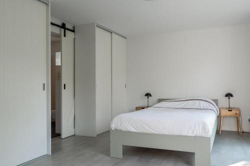 a bedroom with white walls and a white bed at Prachtig genieten in het groen met royale tuin in Hansweert