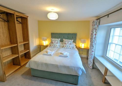 a bedroom with a large white bed with two lamps at Skelwith Fold Cottage No.3 in Elterwater