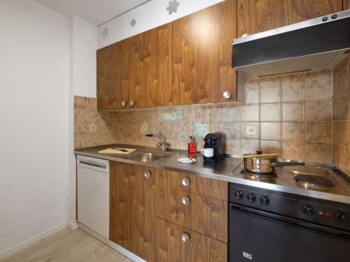 cocina con armarios de madera, fregadero y fogones en Apartment Allod Park Haus C 306 by Interhome, en Davos