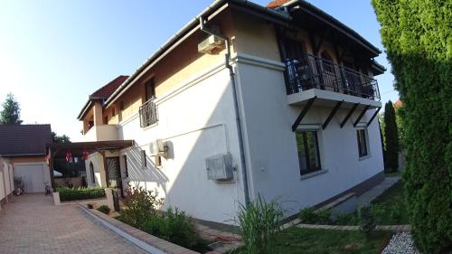 a white building with a balcony on the side of it at Villa Szófia in Siófok