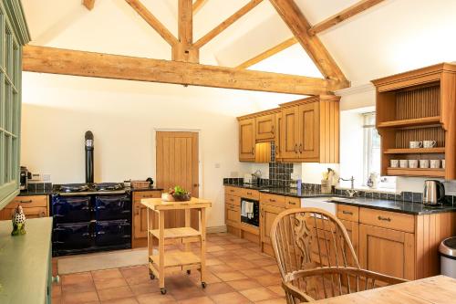 a kitchen with wooden cabinets and a table and chairs at Priory Courtyard - 3 Bedroom Countryside Escape 