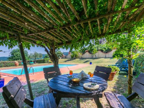 a table and chairs under a pergola next to a pool at Apartment Stalla by Interhome in Sasso Pisano