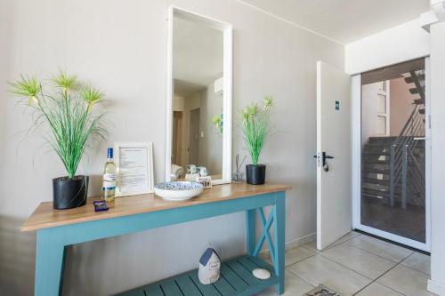 a blue console table with two potted plants on it at Ocean Pearl at Chakas Cove - Beachfront Apartment in Ballito