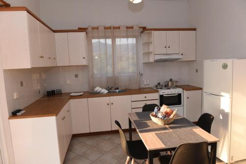 a kitchen with white cabinets and a table with chairs at Denaxas Apartments in Elia Laconias