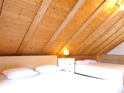 two beds in a room with a wooden ceiling at Holiday Home Rustico Pamela by Interhome in Chiavasco