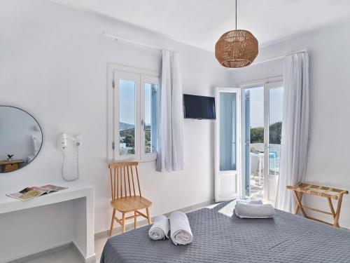 a bedroom with a bed and a desk and windows at Akrotiri Hotel in Parikia