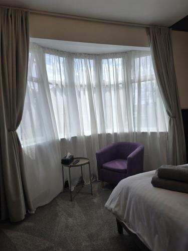 a bedroom with a bed and a purple chair and a window at Double Room with Ensuite Bathroom in Feltham