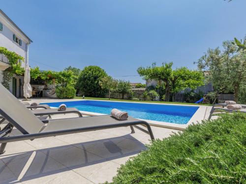a swimming pool with a chaise lounge next to a pool at Holiday Home Villa Radovani by Interhome in Višnjan