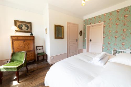 a bedroom with a white bed and a chair at Domaine hotel de France in Cunfin