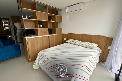 a bedroom with a bed with a wooden headboard at Apto Studio para 03 pessoas em Torres - Ar condicionado - Smart TV - Wifi - Vaga de garagem - Lavanderia - Aceita Pet - 400mts da Praia in Torres