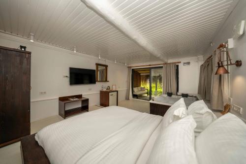 a bedroom with a large white bed and a television at Lov Faralya Adults Only in Faralya