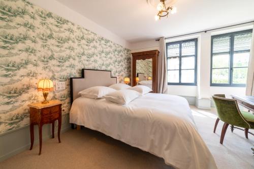 a bedroom with a large white bed with floral wallpaper at Domaine hotel de France in Cunfin
