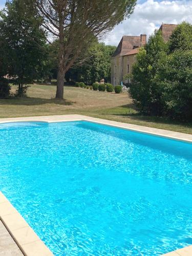 a large blue swimming pool in front of a house at Chateau de Russas, chambre d'hote in Saint-Adjutory