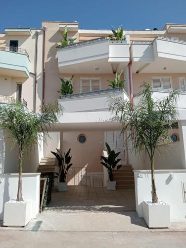 a building with palm trees in front of it at Leo Rooms & Sea in Torre San Giovanni Ugento