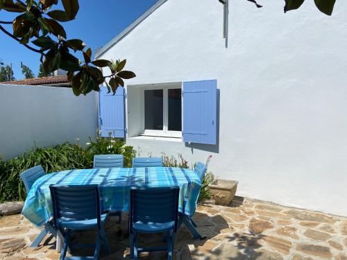 une table et des chaises bleues devant un bâtiment blanc dans l'établissement La Petite Hilairoise, à Saint-Hilaire-de-Riez