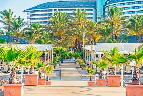 a boardwalk with palm trees and a building at Royal Wings Hotel in Lara
