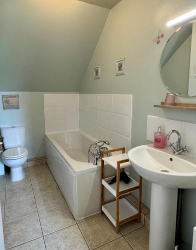 une salle de bain avec une baignoire, un lavabo et des toilettes dans l'établissement Chambre de Jeanne - Le Refuge des Parachutistes - en bordure du marais, à Neuville-au-Plain