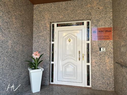 a white door with a plant in front of it at Hostal Valderas in Valderas
